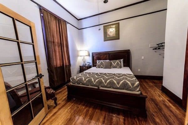 Deluxe room with a dark wooden bed and a patterned gray bedspread