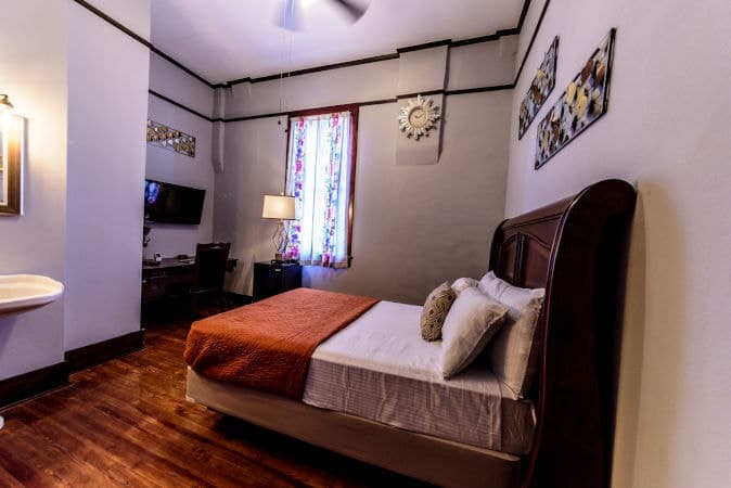 Junior room with a dark wooden bed, orange throw and patterned window curtains