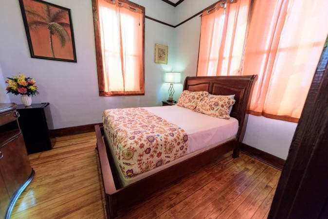 Signature room with a wooden bed, floral bedspread and peach curtains
